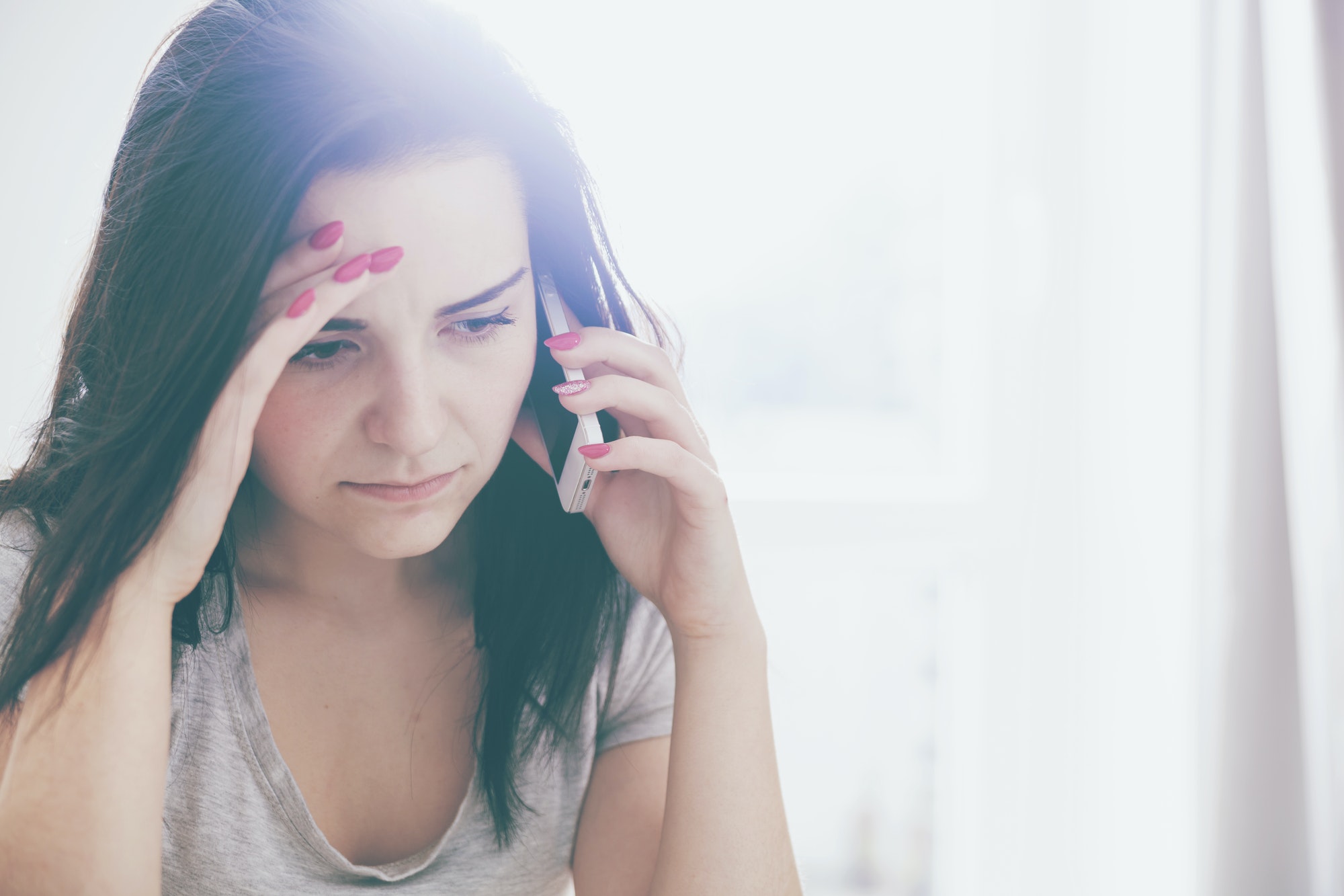 Unhappy worried woman talking on phone at home